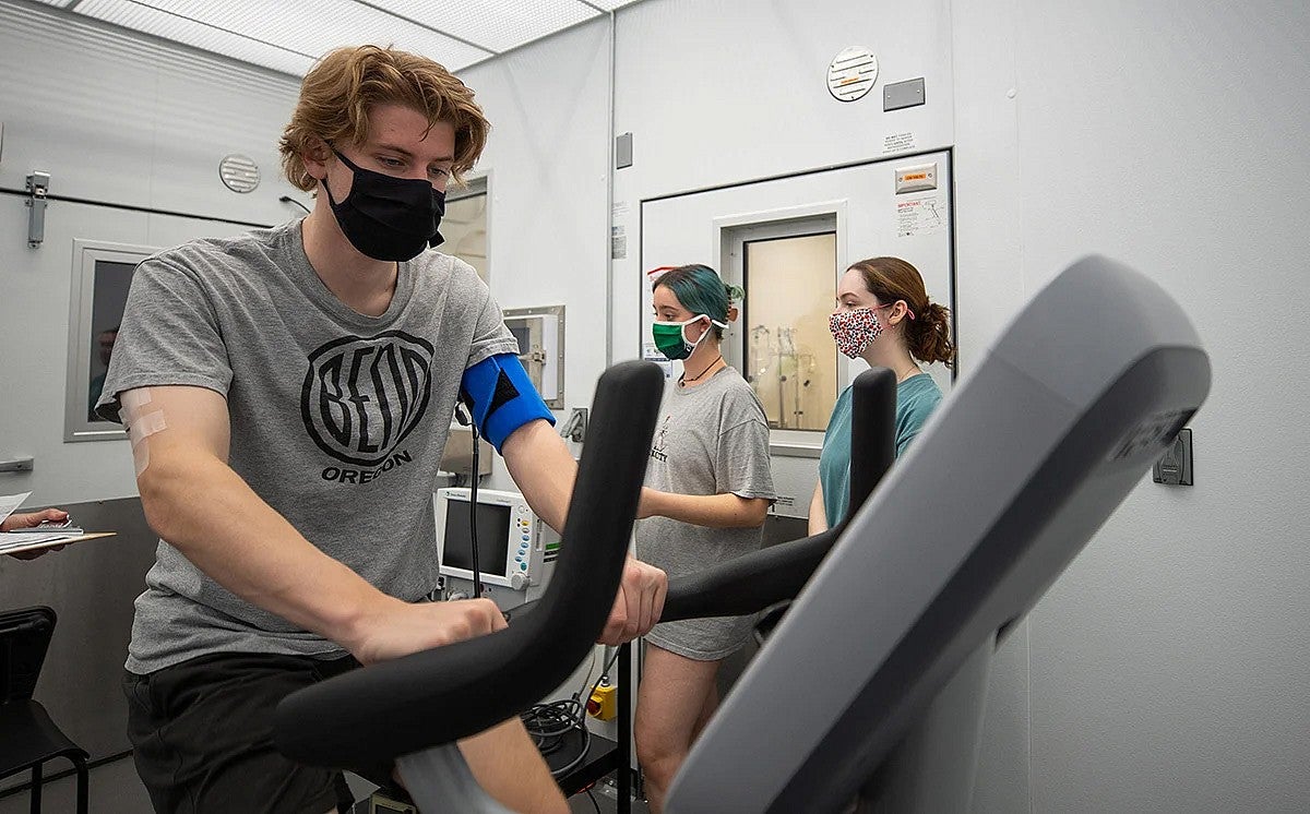 Person wearing a mask on a stationary bike in a research facility