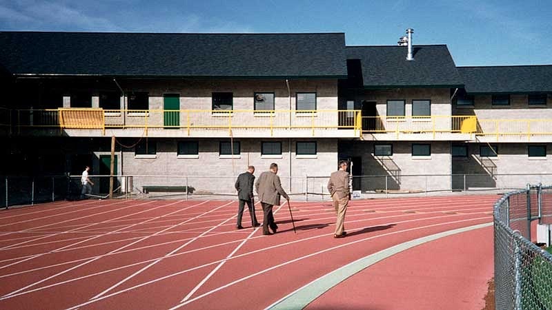 Former track coach Bill Bowerman and two other men walking on the Hayward Field track, away from camera towards the Bowerman Building Former track coach Bill Bowerman and two other men walking on the Hayward Field track, away from camera towards the Bowerman Building