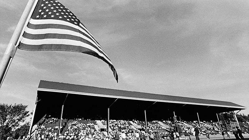 The east grandstand at Hayward Field taken during a late 1960s meet, with an American flag in the foreground at left.